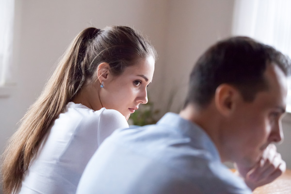 Die Reduktion des Harmoniebedürfnisses kann Probleme vorbeugen bei der BEtroffene ein zu stark ausgeprägtes Harmoniebedürfnis haben. Dies veranschaulicht das Bild, bei dem eine Frau sorgenvoll zu ihrem Partner blickt, Dieser wiederum eher genervt dreinschaut.